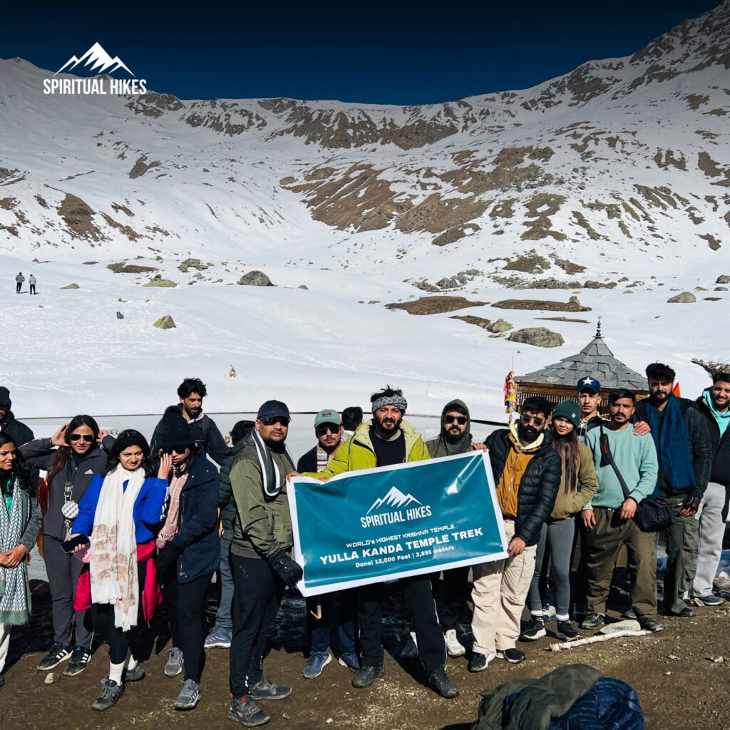 Trekkers at Yulla Kanda Temple Trek surrounded by snowy Himalayan mountains in Himachal Pradesh