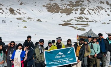 Trekkers at Yulla Kanda Temple Trek surrounded by snowy Himalayan mountains in Himachal Pradesh